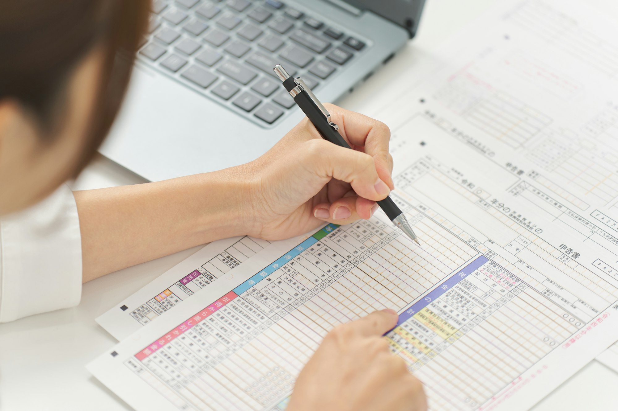 Hand of a woman filling out tax return documents,It says "tax return" in Japanese.