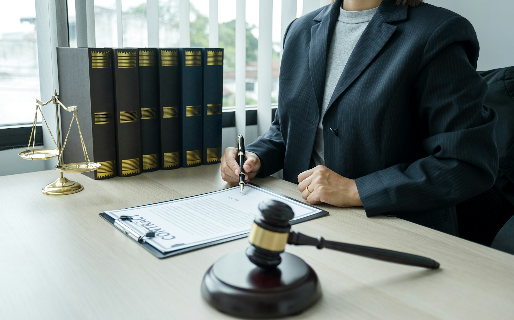 The woman lawyer is sitting at the desk in the office with a justice scale and gavel hammer